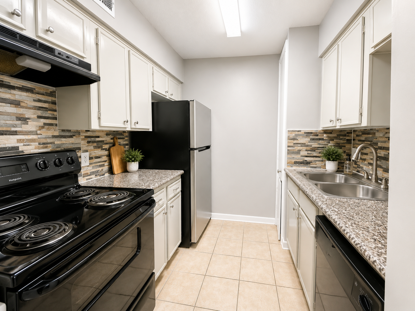 Bright apartment kitchen with white cabinetry and black appliances